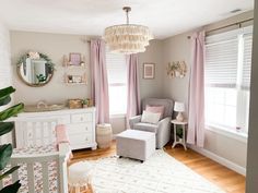 a baby's room with pink drapes, white furniture and a chandelier