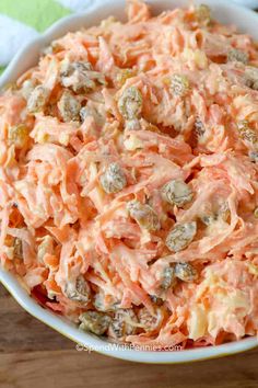 a bowl filled with carrot salad on top of a wooden table