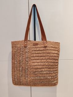 It is hand-knitted from paper thread and raffia metallic thread. It is designed with a waterway pattern. It has a leather handle. It has both a sporty and stylish appearance. It can be carried on the shoulder and in the hand. It is in the saddlebag style. Crochet Woven Leather Shoulder Bag For Shopping, Casual Crochet Bag With Woven Leather And Double Handle, Straw Crochet Bag With Woven Leather And Double Handle, Crochet Straw Bag With Woven Leather And Double Handle, Casual Basket-shaped Crochet Bag With Woven Leather, Casual Woven Leather Crochet Tote Bag, Eco-friendly Jute Crochet Bag With Woven Leather, Eco-friendly Crochet Bag With Woven Leather Details, Eco-friendly Crochet Jute Bag With Woven Leather