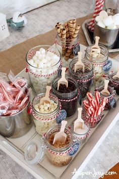 an assortment of candies and marshmallows in glass containers on a tray