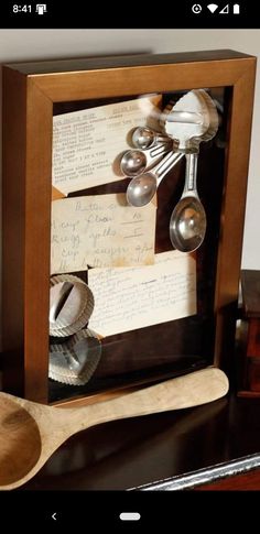 a wooden spoon sitting on top of a table next to a framed object with spoons in it