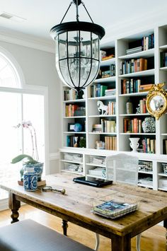 a wooden table sitting in front of a book shelf filled with books