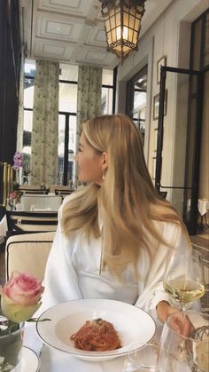 a woman sitting at a table with food and wine