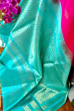 This regal silk cotton saree in hot pink with seafoam blue border and pallu is handwoven. The body is woven with kolam design in gold zari. The saree borders are adorned with traditional motifs in gold zari. The seafoam blue pallu is grand with a rich gold zari work. Approximate Length 6.5 mtrs (inclusive of blouse length) Approximate weight - 1.3 lbs Approximate Height - 44 - 48" Saree comes with fall, picot and tassels done when applicable. Blouse piece is cut. Kindly Note : The colors you see on your device may vary due to the color reproduction, brightness and resolution of individual devices. If you'd like more clarity before your purchase, please contact our support team. Saree Borders, Kolam Design, Seafoam Blue, Saree Border, Traditional Motifs, Blue Border, Silk Cotton Sarees, Kolam Designs, Zari Work