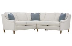 a white sectional couch with blue pillows on it's back and arms, against a white background