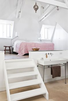 an attic bedroom with stairs leading up to the bed and desks on either side