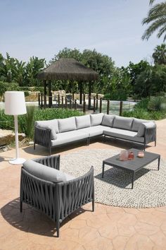 an outdoor living area with couches, tables and lamps on the ground in front of palm trees