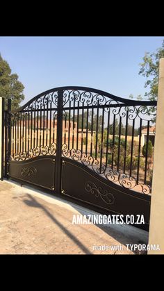 an iron gate with decorative designs on the top and bottom, in front of a house