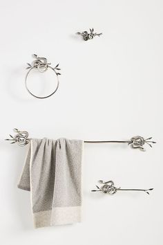 two towels hanging from hooks on a white wall next to towel rings and ring holders