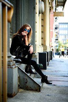 a woman sitting on top of a metal step talking on a cell phone while wearing sunglasses