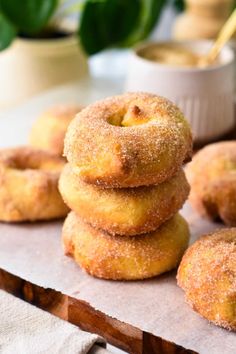 a stack of doughnuts sitting on top of a wooden table next to a bowl of dipping sauce