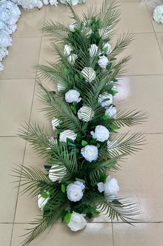 white flowers and greenery are arranged on the floor