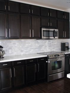 a kitchen with black cabinets and stainless steel appliances