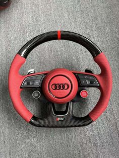 an audi steering wheel with red stitching and black spokes on the inside of it