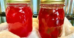 two jars filled with red liquid sitting on top of a white towel next to each other