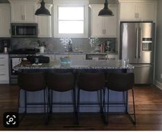 a kitchen with three bar stools in front of an island and stainless steel appliances