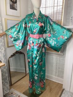 PLEASE READ FULL DESCRIPTION AND REVIEW ALL POSTED MEASUREMENTS AND PHOTOS Lovely and vibrant kimono by Ichiban made in Japan, features gorgeous colors of mainly teals and pink in a floral and peacock print, kimono sleeves with vents, most likely an acetate fabric, that gage is faded and not legible. It is missing the original belt but I will include the one pictured as it complements the look, this pink knot belt is stretch elastic with a hook closure, in  good vintage condition, kimono has been delicate laundered and air dried. One size fits many. Free USPS ground advantage shipping with USPS Priority shipping upgrade option available at checkout for an additional fee if you choose. Measurements taken with garment lying flat, double for full circumference size Pit to pit up to about 24 i Green Long Kimono With Floral Print, Long Green Kimono With Floral Print, Green Long Floral Print Kimono, Long Green Floral Print Kimono, Fitted Long Green Kimono, Traditional Green Kimono For Spring, Fitted Green Spring Kimono, Fitted Green Kimono For Summer, Green Kimono With Kimono Sleeves For Tea Ceremony