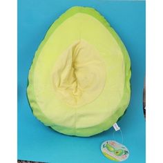 an avocado shaped pillow sitting on top of a blue surface next to a tag