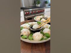 two plates filled with dumplings and chopsticks on top of a wooden table