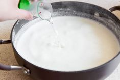 someone is pouring milk into a pan on the stove