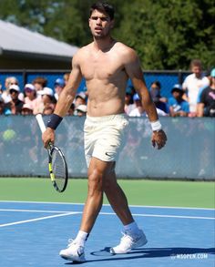 a shirtless man holding a tennis racquet on a court