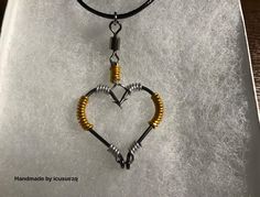 a heart shaped pendant on a black cord with two gold and silver beads hanging from it