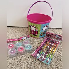 a hello kitty bucket and its contents are on the floor next to some pencils