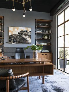 a large wooden desk sitting in front of a book shelf filled with books and vases