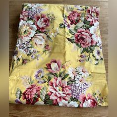 a yellow flowered fabric with pink and white flowers on the bottom, sitting on a wooden floor