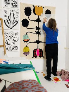 a woman standing in front of a wall hanging art work on it's side