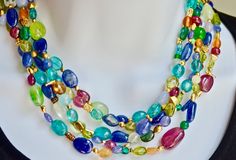 A fusion of primary and secondary colors of natural gemstone beads in this 5 strand torsade. The beads are an assortment of shapes and colors which capture the uniqueness and creativity of the necklace. Included are tourmaline, ruby, lapis, citrine, peridot, agates, sapphire, rock crystal, aquamarine The 18K yellow gold spacers  are also varied in size and shape and contribute to the singularity of the necklace. The necklace has an 18K yellow gold hook clasp closure. weight 147 grams. Unique Multicolor Oval Beads, Elegant Double Strand Multicolor Beads, Elegant Multi-color Double Strand Beads, Elegant Multicolor Double Strand Beads, Multicolor Multi-stone Beads And Cabochons For Jewelry Making, Multicolor Multi-stone Beads For Jewelry Making, Elegant Multicolor Oval Beads, Gems, And Cabochons, Elegant Multicolor Oval Beads Gems And Cabochons, Elegant Multicolor Polished Gemstone Beads