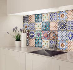 a kitchen counter with a sink and tiled backsplash in front of white cabinets