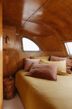 there is a bed with many pillows in the cabin on this boat that is made up