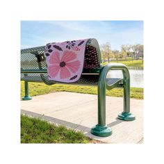 a green park bench with a pink blanket on it's back and two metal handrails