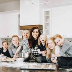 a group of children and their mother in the kitchen posing for a photo with them