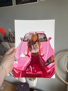 a person holding up a pink car with a woman's face on it