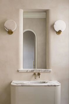 a white sink sitting under a mirror next to a wall mounted faucet in a bathroom