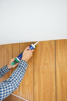 a man is painting the wall with blue and white paint on wood planks in his home