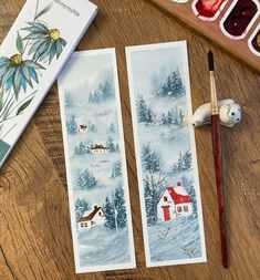 two watercolors are sitting on a table next to some paintbrushes