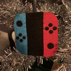 an ornament hanging from a christmas tree decorated with video game controller buttons and tinsel