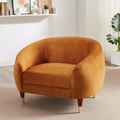 an orange chair sitting on top of a carpeted floor next to a potted plant