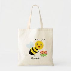 a tote bag with a cartoon bee on it and flowers in the back ground