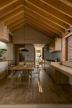 an open kitchen and dining area with wood flooring, white walls and wooden beams