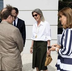 two women and one man are talking to each other in front of a white building