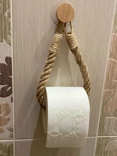 a rope wrapped toilet paper holder hangs on the wall