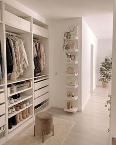 a walk in closet with white shelving and shelves filled with shoes, sweaters and other items