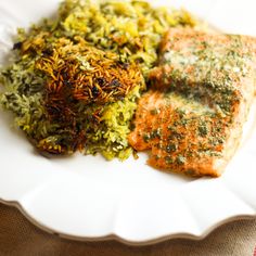 a white plate topped with fish and rice covered in seasoning next to broccoli