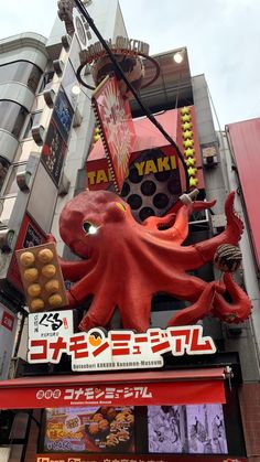 an octopus sign on the side of a building in japan with other signs above it