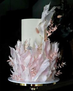 a white and pink wedding cake with flowers on top