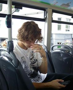 a young man sitting on a bus looking at his cell phone